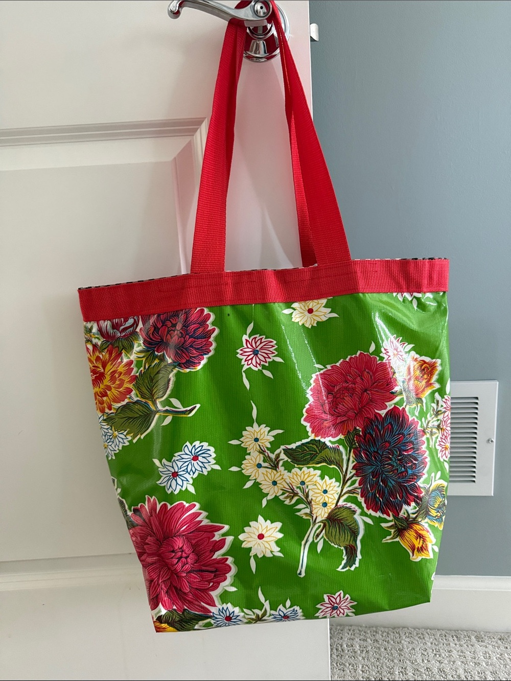Plastic coated green and red floral bag with red straps